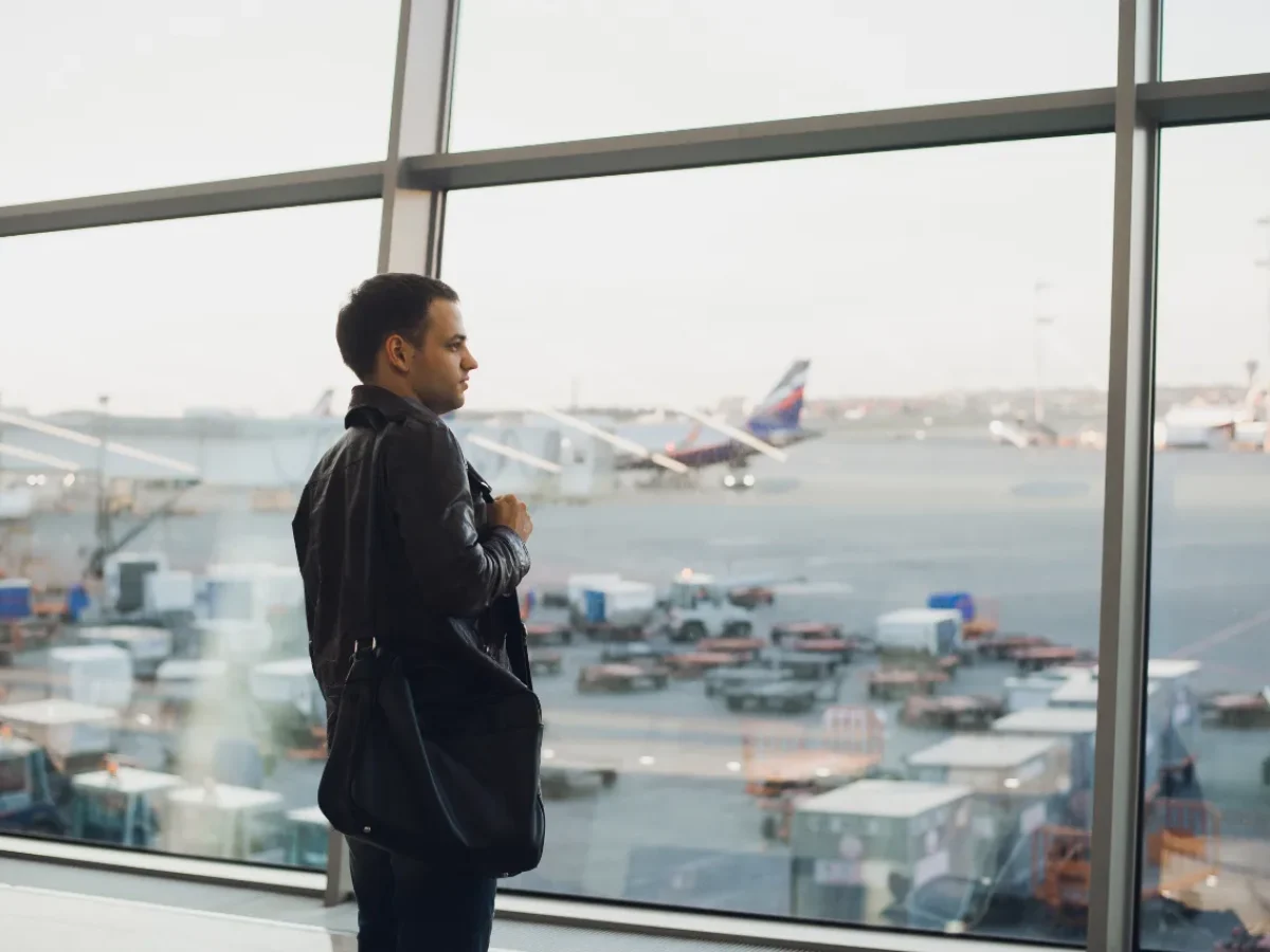 un hombre esperando su vuelo en la ventana del aeropuerto